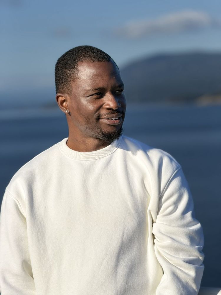 Nas by the water in a white sweater