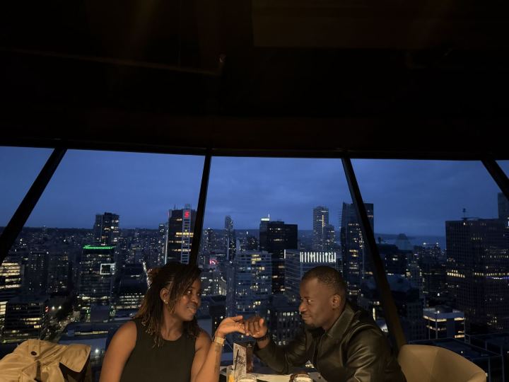 Nas and Praise at dinner, city lights behind